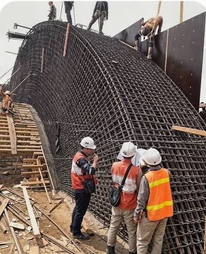 Workers constructing a large curved reinforcement cage