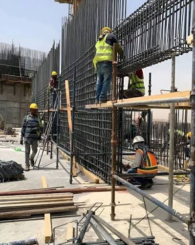 Workers tying wall reinforcement at a multi-storey construction site